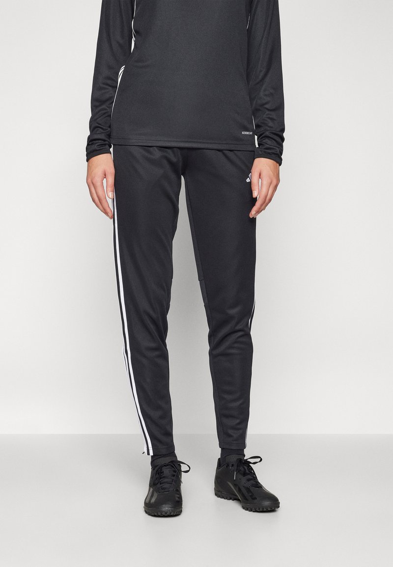 Schwarzes Sportoutfit bestehend aus einem Langarmshirt und taillierten Hosen mit weißen seitlichen Streifen. Der Stoff ist glatt, und das Design ist figurbetont.