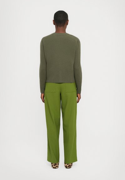 Olive green knitted sweater with ribbed hem, paired with high-waisted lime green wide-leg trousers. Accessories feature leopard print heels.