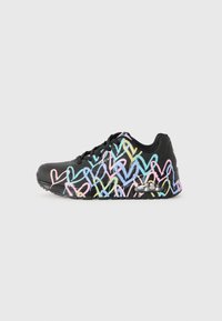 Baskets noires avec des motifs de cœurs pastel multicolores, semelle à coussin d'air transparente et lacets noirs sur un fond blanc.