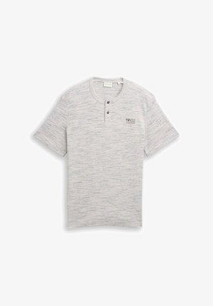 Šviesiai pilka trumpomis rankovėmis Henley marškinėliai su subtiliomis horizontaliosiomis juostelėmis, dviem juodais mygtukais ant apykaklės ir užrašu „19/62“ ant krūtinės.