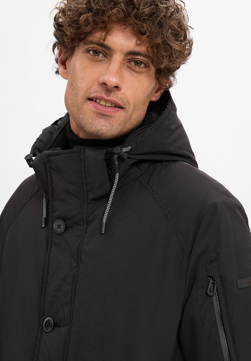 Czarna ocieplana kurtka z kapturem, z przodu zapinana na guziki, z akcentami w postaci sznureczków oraz bocznymi kieszeniami na zamek. Gładka tekstura i minimalistyczny design.