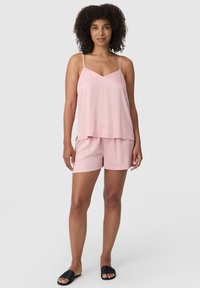 Jasnoróżowy zestaw do spania składający się z luźnego topu na ramiączkach z regulacją i dopasowanych szortów. Miękka tkanina o gładkiej fakturze.