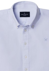 Jasnoniebieska, w paski koszula z guzikami z bawełny, z klasycznym kołnierzykiem. Posiada białe guziki oraz małe, haftowane logo na piersi.