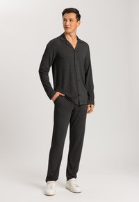 Donkergrijze, langjarige knopbloes met een notched kraag, gecombineerd met bijpassende slim-fit broek en witte sneakers. Zachte stoftextuur.