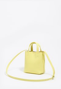 Mała żółta skórzana torebka z krótkimi uchwytami i długim regulowanym paskiem, na jednolitym białym tle.