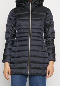 Sort dunjakke med hætte, prydet med vandret quiltet design, hel lynlås og elastiske manchetter. Glat, skinnende materiale.