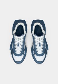 Μπλε και λευκά αθλητικά παπούτσια με ανώτερο μέρος από υφή διχτυού, λαστιχένια σόλα και επενδεδυμένο γιακά. Διαθέτουν αντίθετες πλευρικές επιφάνειες και κορδόνια.