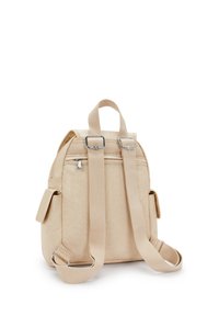 Zaino in tela beige con spallacci regolabili, tasca frontale con zip, tasca laterale e dettagli metallici argentati. Superficie testurizzata e forma moderna.