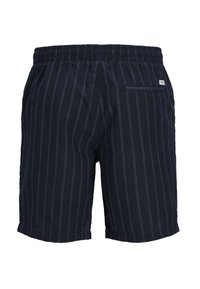 Shorts bleu marine avec des rayures blanches verticales, taille élastique et une poche arrière avec une étiquette de marque. Texture de tissu douce.