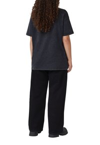 Donkergrijze oversized t-shirt van katoen, gecombineerd met zwarte wijde broek, beide met een ontspannen pasvorm en minimale stikseldetails.
