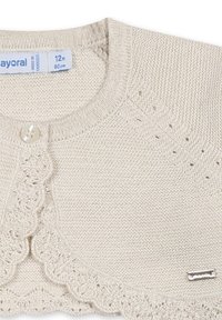 Cardigan en tricot beige avec finition en dentelle, col rond et fermeture à un bouton. Comprend une petite étiquette métallique sur le devant.