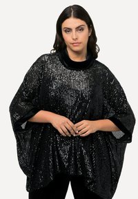 Poncho negro con lentejuelas, de silueta amplia y con ribetes de terciopelo en el escote y los puños. Presenta lentejuelas brillantes en toda la tela.