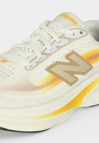 Λευκό και κίτρινο παπούτσι για τρέξιμο New Balance με μπεζ λογότυπο, δέσιμο με κορδόνια και ανθεκτικό αεριζόμενο διχτυωτό επάνω μέρος.