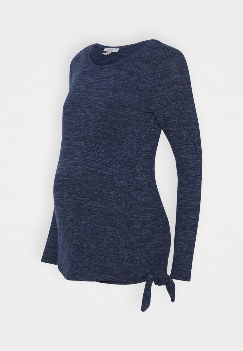 Haut de maternité bleu marine à manches longues en tissu doux et texturé, avec un détail nœud sur le côté et un ourlet arrondi pour une coupe décontractée.