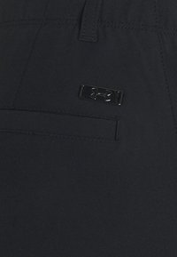 Svarta träningsshorts med en slät yta, som har en sydd ficka och en silverfärgad logotagg på midjebandet.