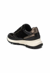 Sneaker in suede e pelle nera con un accento in bronzo, caratterizzato da una spessa intersuola bianca e una suola in gomma nera texture. Borchie laterali visibili.