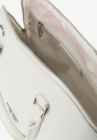 Interno di una borsa sintetica bianca, con fodera rosa chiaro, scomparto con zip e accessori in metallo argentato. Nessuna tasca esterna visibile.