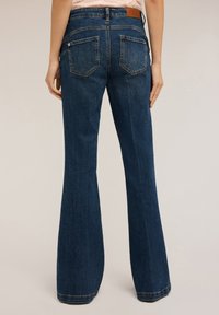 Donkerblauwe flared jeans met een hoge taille, voorzien van vijf zakken, minimale stiksels en een leren logo-opdruk op de achterkant van de tailleband.