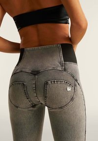 Housut harmaasta denimestä, joissa on korkea vyötärö ja musta joustava vyötärönauha. Sisältää kaksi pyöristettyä takataskua ja ommeltuja yksityiskohtia sivuilla.