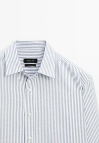 Camicia a righe blu chiaro e bianco, realizzata in tessuto lavorato. Presenta un colletto a punta e chiusura a bottoni, con un'etichetta del marchio all'interno.