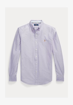 Camisa de botones en color lavanda, hecha de una tela ligera, con cuello clásico, mangas largas y un pequeño logo bordado en el lado izquierdo del pecho.