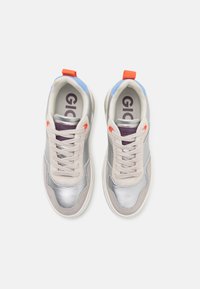 Baskets avec une tige métallisée argentée, des accents en suede gris clair, des détails violets et orange, et un onglet au talon bleu. Lacets dans une teinte neutre.
