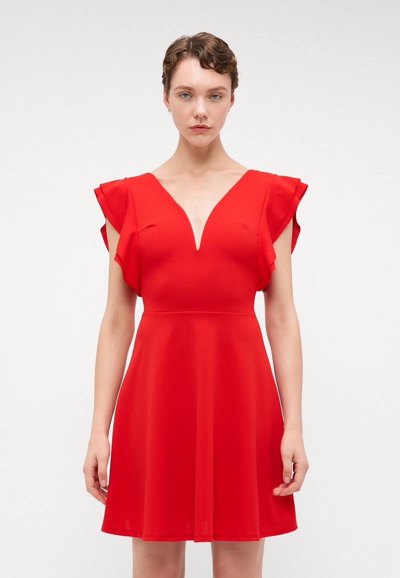 Robe rouge en tissu lisse, dotée d'un décolleté en V profond, de manches courtes à volants et d'un corsage ajusté qui s'évase à la taille.