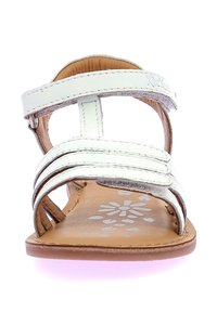 Sandalia de piel blanca con tres tiras, diseño de punta abierta, plantilla de cuero natural y patrón floral en la base. Suela plana.