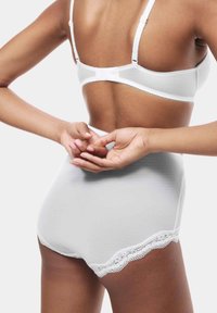 Wit bh met kantafwerking en hoge taille slip. Zacht, gestructureerd materiaal met fijne klokrand en verstelbare banden.