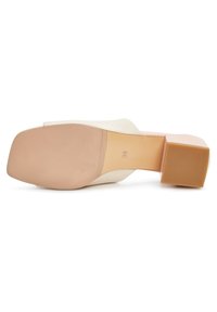 Semelle d'une mule beige avec un bout carré, un talon bloc, une semelle texturée et la taille 38 indiquée sur la semelle intérieure.