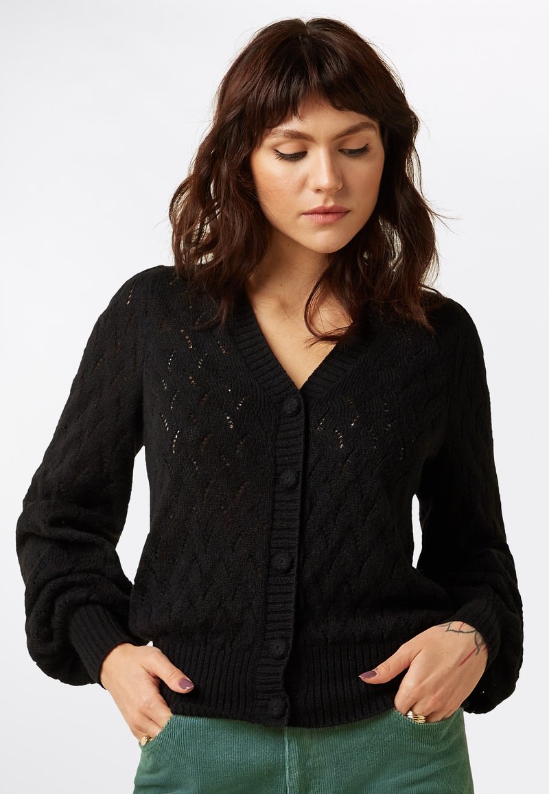 Cardigan negro de punto con un patrón de diamantes, mangas largas, escote en V y cierre de botones. Los puños y el dobladillo acanalados añaden textura al diseño.