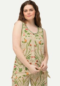 Top in tessuto floreale beige con bordi verdi, decorato con un motivo di fiori rossi e arancioni e foglie verdi. Realizzato in tessuto morbido e traspirante.