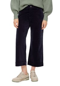 Navy corduroy wijde-pijpenbroeken, met een voorste knoopsluiting, opgerolde mouwen en een egale textuur, gecombineerd met lichtgekleurde sneakers.