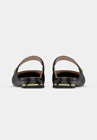 Μαύρα παπούτσια από πατινέ δέρμα με ανοιχτή φτέρνα, χαμηλό τακούνι, χρυσή λωρίδα διακόσμησης στη σόλα και λεία, γυαλιστερή επιφάνεια.