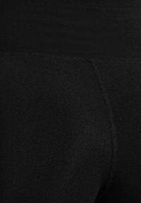 Zwarte leggings van rekbaar materiaal, met een hoge tailleband en een zachte textuur, voorzien van platte naden voor een gestroomlijnd uiterlijk.