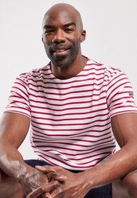 Camiseta a rayas rojas y blancas en un estilo ajustado, hecha de algodón, con cuello redondo y mangas cortas, combinada con pantalones cortos azul marino.