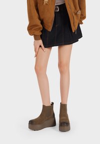 Stivaletti in suede marrone con suola a piattaforma spessa, dotati di punta arrotondata e pannelli laterali elasticizzati per un facile indossamento.