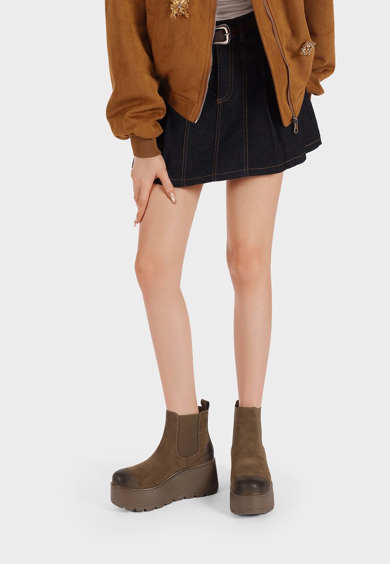 Stivaletti in suede marrone con suola a piattaforma spessa, dotati di punta arrotondata e pannelli laterali elasticizzati per un facile indossamento.