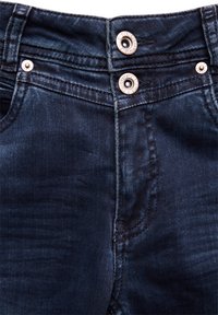 Jeans en denim foncé avec une coupe ajustée, deux boutons en argent à la taille et des détails de couture subtils à l'avant.