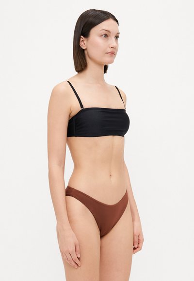 Musta bandeau-bikini yläosa ohuilla hihnoilla ja sileällä pinnalla, yhdistettynä ruskeisiin matalavyötäröisiin bikinitikkuihin, joissa on kaareva viivakuosi.