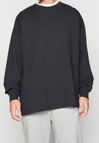 Svart långärmad t-shirt i bomull med rund hals. Har en liten broderad Nike-logotyp vid bröstet. Löst passform.