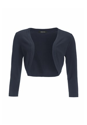 Cardigan court bleu marine, manches longues, tissu doux, design ouvert à l'avant, sans fermetures, texture lisse, style minimaliste, étiquettes visibles à l'intérieur.