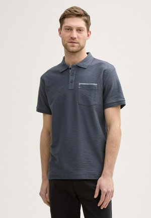 Dark blue polo shirt made from textured fabric, featuring a three-button placket and a chest pocket with a contrasting design.