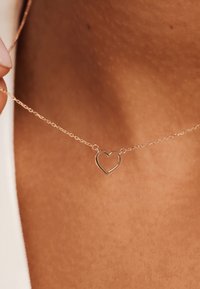 Roze gouden ketting met een open hart hanger. Het hart is omrand en hangt aan een delicaat kettinkje.