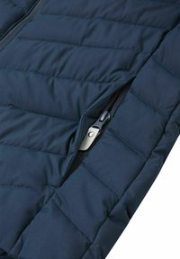 Granatowa ocieplana kurtka z pikowaną teksturą, z kieszenią na zamek błyskawiczny i wytrzymałym materiałem. Powierzchnia ma gładkie wykończenie.