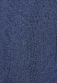 Primer plano de una tela de punto densa y texturizada de color azul marino, con costillas verticales visibles y finos detalles tejidos.