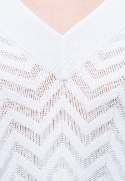 Άσπρο πλεκτό πουλόβερ με λαιμόκοψη σε σχήμα V και ζιγκ-ζαγκ μοτίβο με υφή. Ελαφρύ και ημιδιαφανές ύφασμα που ενισχύει την αναπνοή.