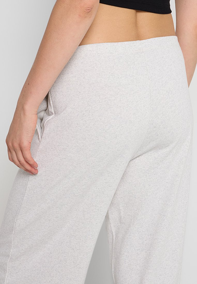 Pantaloni grigi, leggeri, in misto cotone con vestibilità ampia. Presentano una superficie liscia e tasche laterali, mostrati da dietro.