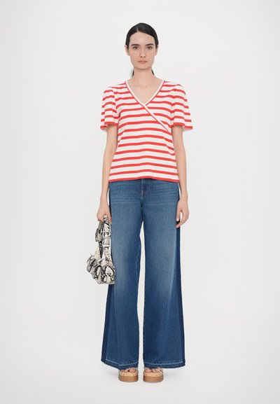 Red and white striped short-sleeve top with a V-neck, paired with wide-leg blue denim jeans. Accessories include a textured black and white bag.