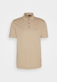 Polo beige à manches courtes avec trois boutons et petit logo brodé sur le côté gauche de la poitrine.